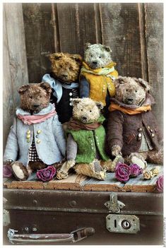 five teddy bears sitting on top of an old suitcase