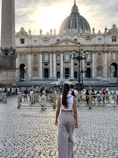 a woman standing in front of a large building with a tall obelisk on it's side