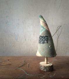 a small green and white christmas tree sitting on top of a wooden table next to string