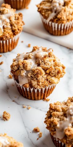 muffins with icing and crumbs sitting on a marble counter top