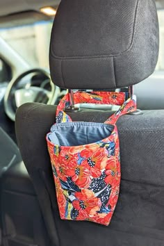 an orange flowered purse hanging from the back seat of a car with its pocket open