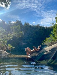 a woman laying on top of a log in the water