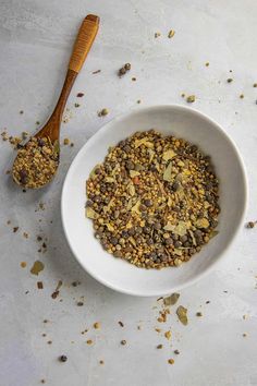 a white bowl filled with granola next to a wooden spoon on top of a table