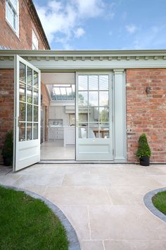 an open door leading to a kitchen in a brick building with green grass around it