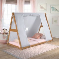 a child's bed with a tent on the top and pink pillows underneath it