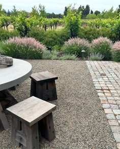 an outdoor table and two stools in the middle of a graveled patio area