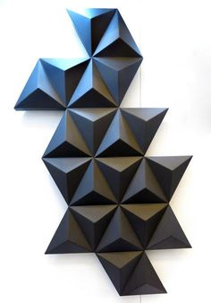 an abstract sculpture made out of black cubes on a white wall in the shape of a star