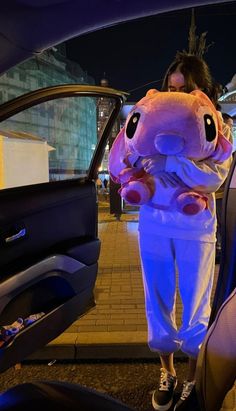 a woman is standing in the back seat of a car with an elephant stuffed animal on her chest