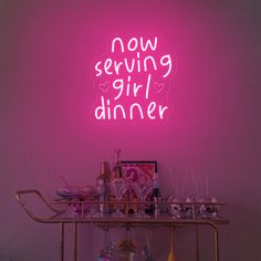 a pink neon sign that says now serving girl dinner on a bar cart in front of a purple wall