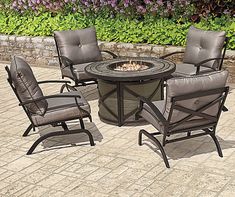 an outdoor fire pit set with four chairs and a round table on a brick patio