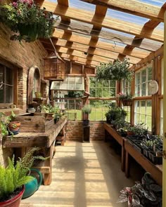 a room filled with lots of potted plants next to a wooden table and windows