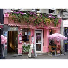 a pink building with flowers on the windows and an open umbrella in front of it