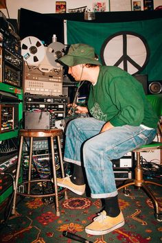 a man sitting on top of a stool in front of an assortment of electronic equipment