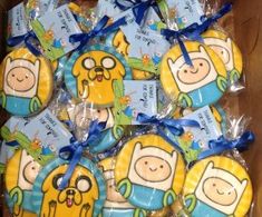 a box full of cartoon character cookies wrapped in cellophane with blue ribbon and bow