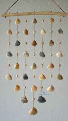 a mobile made out of seashells hanging from a wooden frame on a wall