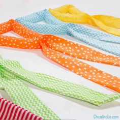 four different colored ties laid out on a white surface with polka dots and chevron stripes