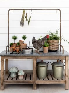 an outdoor table with pots and plants on it