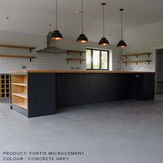 an empty kitchen with black cabinets and hanging lights above the countertop, along with open shelving units