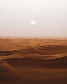 the sun is setting in the desert with sand dunes and footprints on the ground below