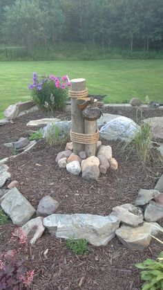 a fire hydrant sitting in the middle of a garden surrounded by rocks and flowers