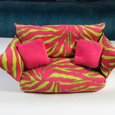 a pink and green chair with two pillows on it