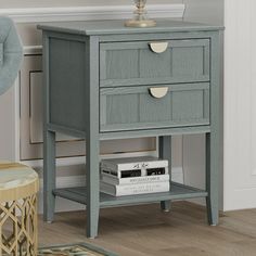 a nightstand with two drawers and a lamp on it next to a chair in a room