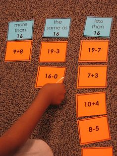 a child is writing numbers on the floor with orange sticky notes attached to each side