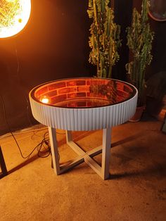 a table made out of an old tub is lit up by a lamp on the floor