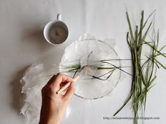 a person is painting flowers on a glass plate with white paper and some green grass