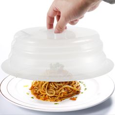 a person is reaching for spaghetti on a plate with a plastic cover over the top