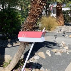 a red and white mailbox sitting next to a palm tree