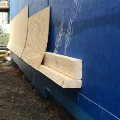 there is a bench made out of plywood on the side of a building that's being built