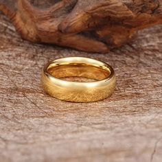 a gold wedding ring sitting on top of a piece of wood