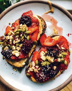 two pieces of toast topped with fruit and nuts on top of a white plate next to a potted plant