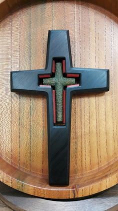 a wooden cross on top of a barrel with wood in the bottom and red trim