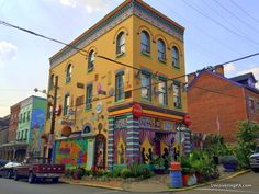 an old building painted in bright colors on the corner of a street with parked cars