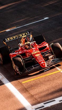 a man driving a red race car down a street