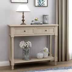 a table with two vases on top of it next to a lamp and pictures