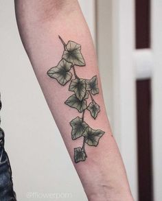 a tattoo on the arm of a woman with green leaves