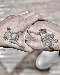 two hands holding each other with tattoos on them