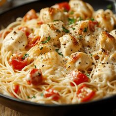 pasta with chicken and tomatoes in a skillet on a wooden table, ready to be eaten