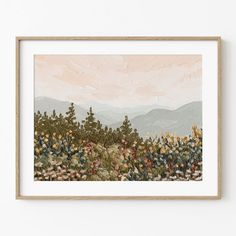 a painting hanging on a wall next to a wooden framed art print with mountains in the background