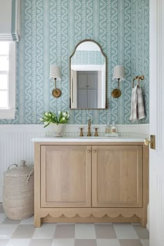 a bathroom with blue and white wallpaper, wooden cabinets and a large mirror above the sink