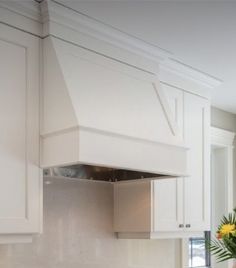 a kitchen with white cabinets and stainless steel stove top hood over the range in front of an oven