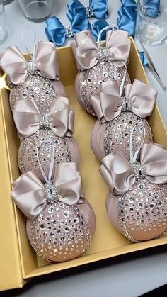 several pairs of pink shoes with bows on them in a box next to silver and blue napkins