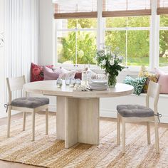 a dining table with two chairs and a bench in front of a window that has flowers on it