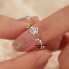 a woman's hand holding a diamond ring in her left hand, with the engagement band on it