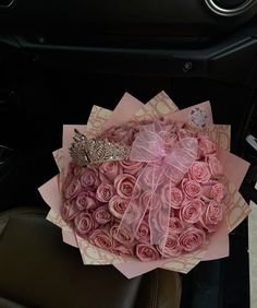 a bouquet of pink roses sitting in the center of a car seat with a bow on it