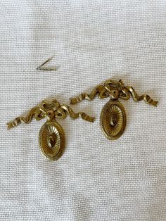 a pair of gold metal pulls on a white cloth