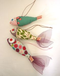 two fish made out of fabric and string on a white surface, one is green and the other is red